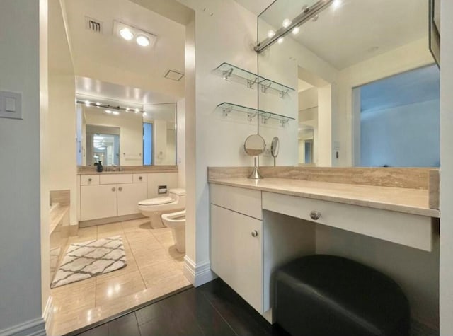bathroom featuring visible vents, toilet, vanity, a bidet, and a bath