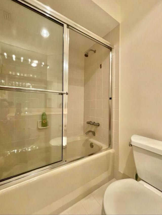 bathroom with toilet, enclosed tub / shower combo, and tile patterned floors