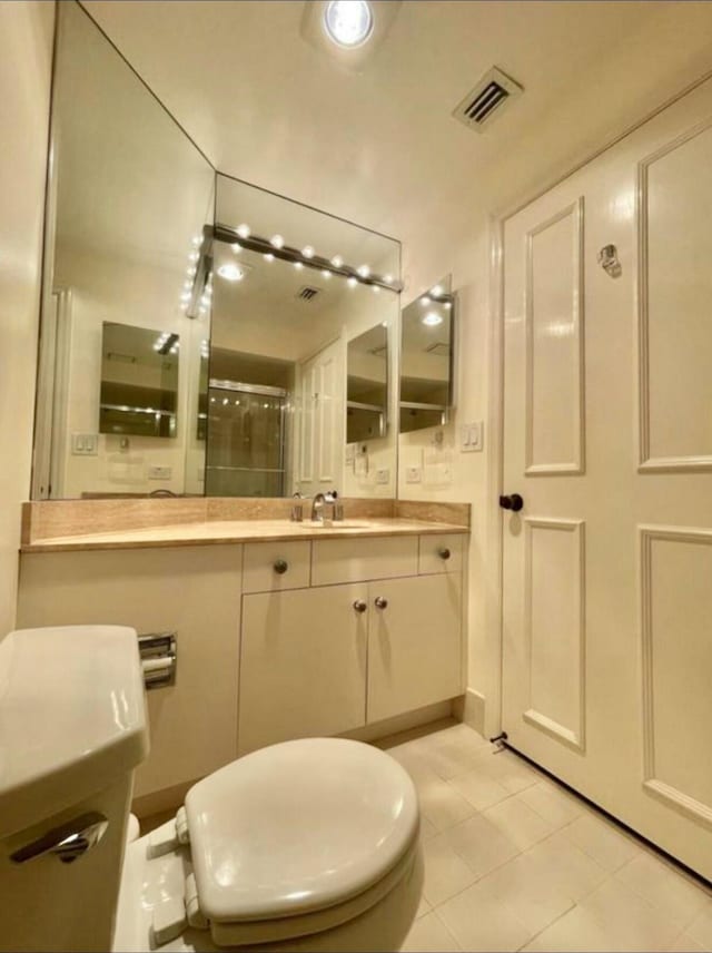 bathroom featuring visible vents, toilet, an enclosed shower, vanity, and tile patterned flooring