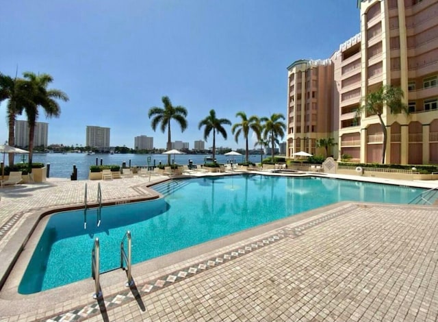 community pool featuring a view of city, a water view, and a patio