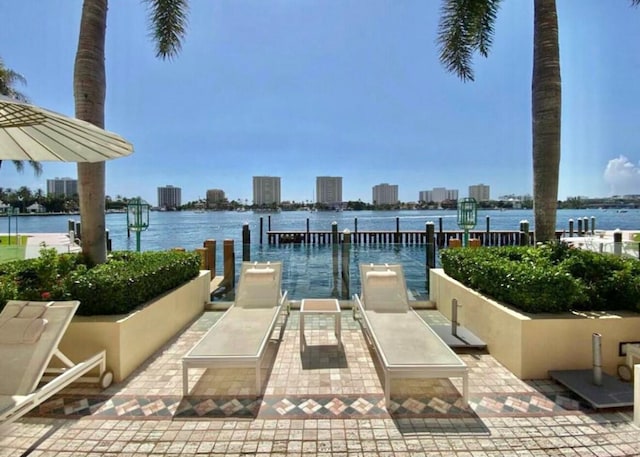 view of patio featuring a dock, a water view, and a city view