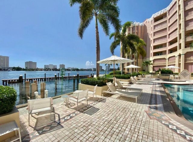 view of pool featuring a view of city, a patio, and a water view