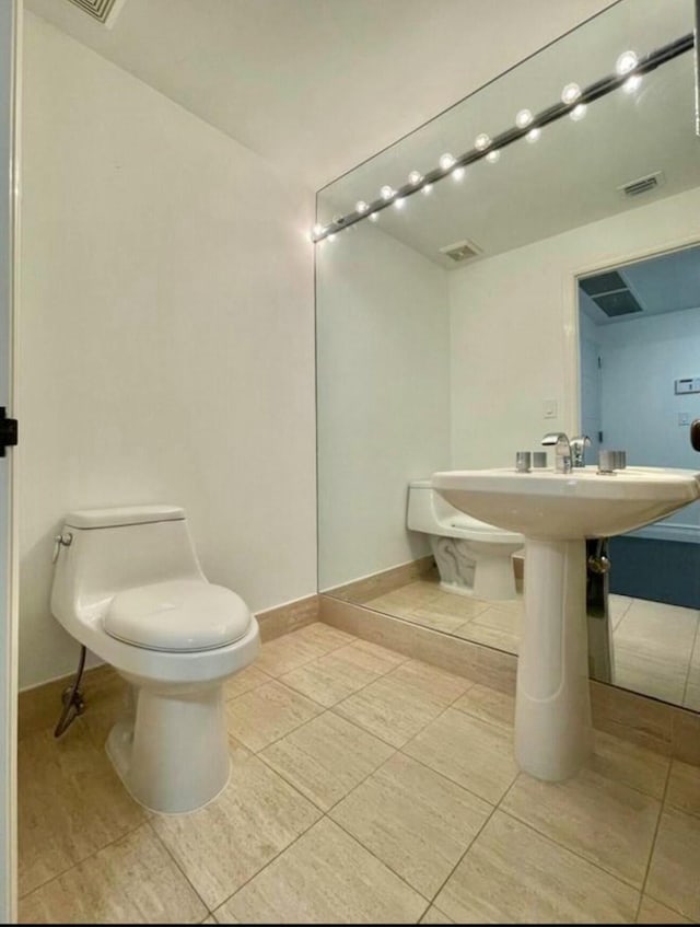 bathroom featuring toilet, visible vents, and baseboards