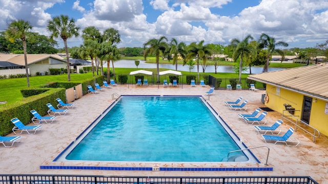 community pool with a patio, a water view, and fence