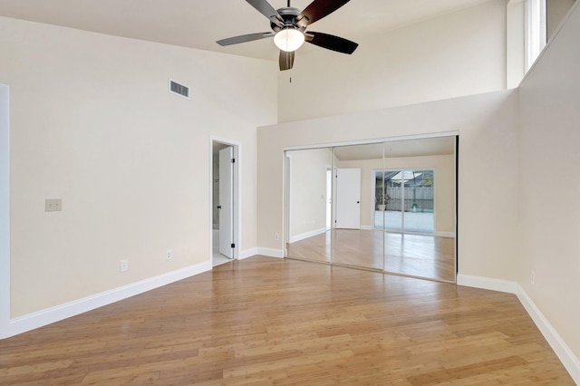 interior space with a high ceiling, visible vents, light wood-style flooring, and baseboards