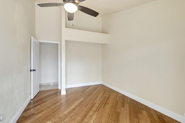 empty room featuring a ceiling fan, vaulted ceiling, baseboards, and wood finished floors