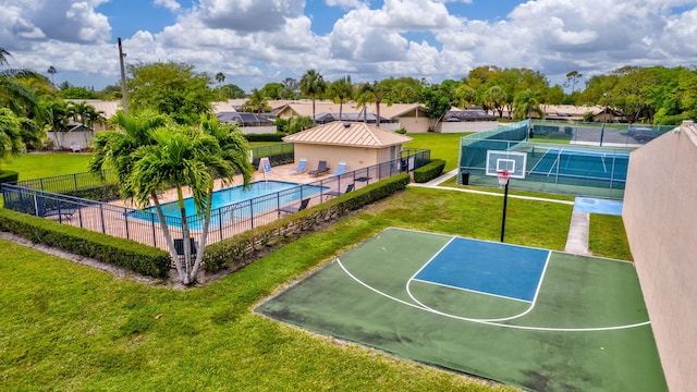 view of sport court featuring a community pool, fence, community basketball court, a lawn, and a residential view