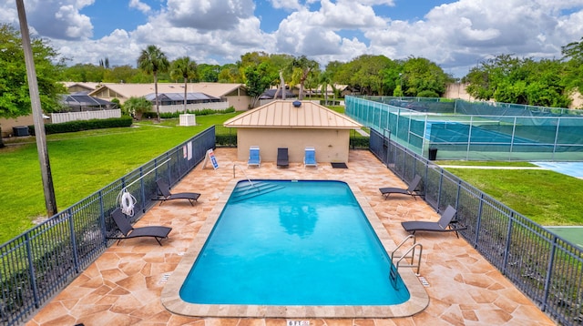 pool featuring a patio, a lawn, and fence