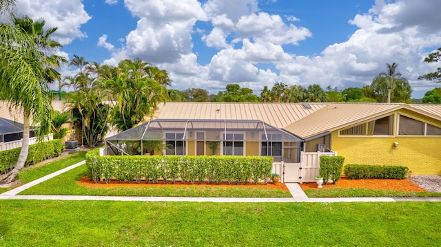 view of front facade featuring metal roof, a lanai, brick siding, a front lawn, and a standing seam roof