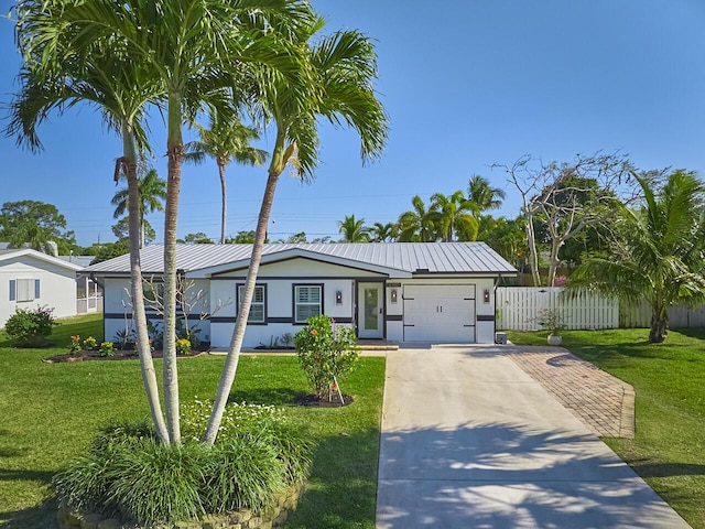 view of front of house with driveway, fence, a front yard, an attached garage, and metal roof