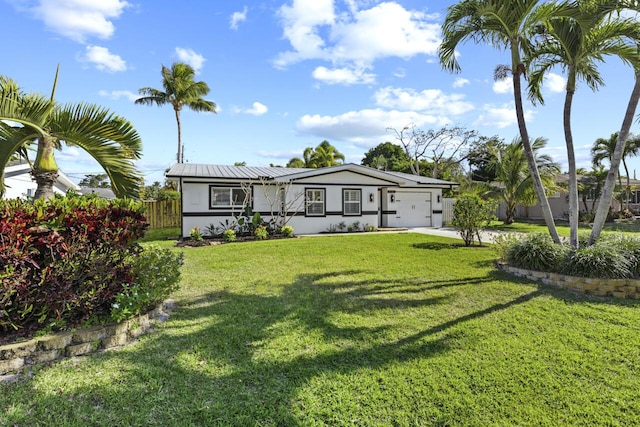 view of front of house featuring a front yard, fence, driveway, a garage, and metal roof