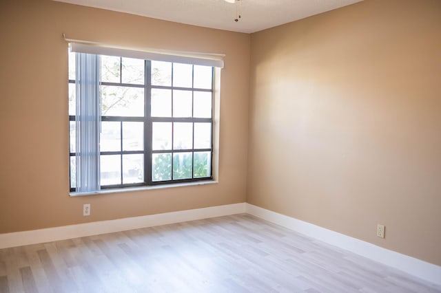 spare room with a healthy amount of sunlight, baseboards, and wood finished floors