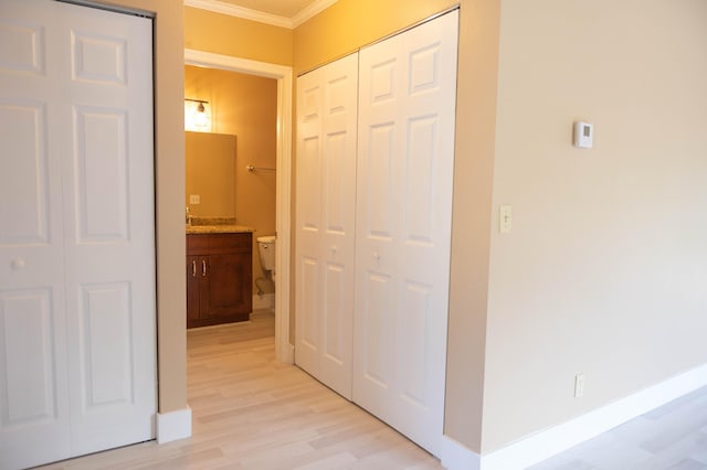 hallway featuring light wood finished floors, baseboards, and ornamental molding