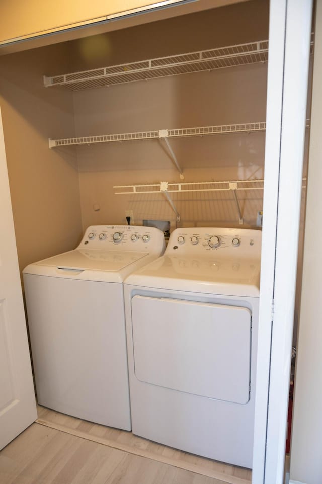 laundry area with light wood-type flooring, laundry area, and washing machine and clothes dryer