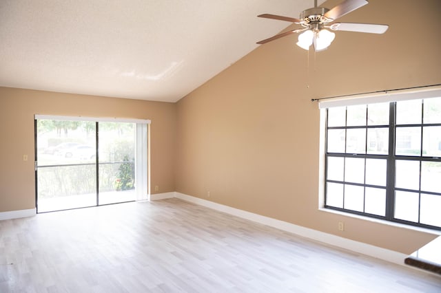 empty room featuring lofted ceiling, light wood-style flooring, baseboards, and ceiling fan