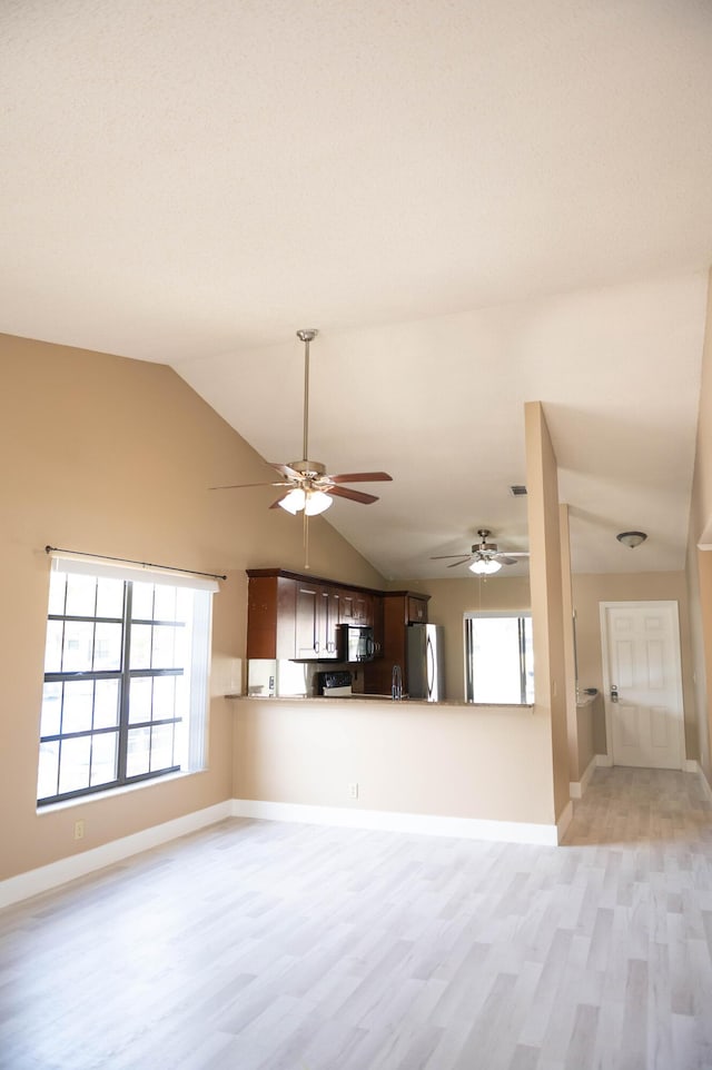 unfurnished living room featuring vaulted ceiling, light wood finished floors, and baseboards