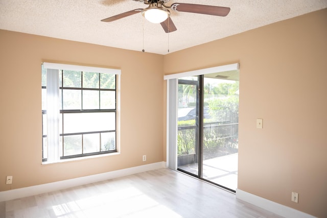 spare room featuring a ceiling fan, baseboards, a textured ceiling, and wood finished floors