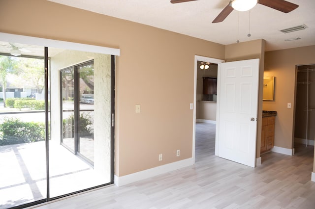 interior space with light wood-style flooring, visible vents, ceiling fan, and baseboards