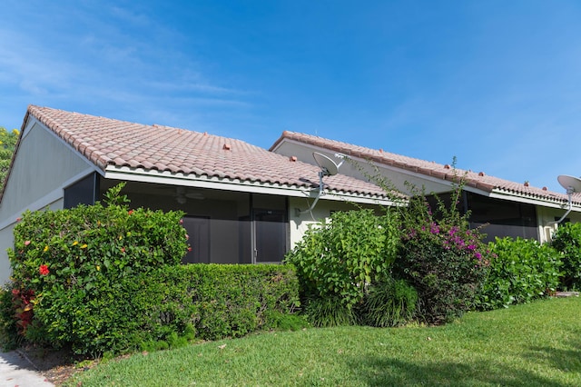 rear view of house featuring a tile roof and a lawn