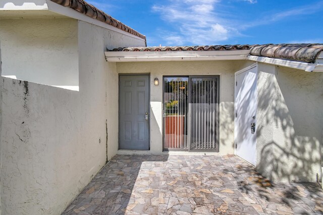 doorway to property with a tiled roof and stucco siding