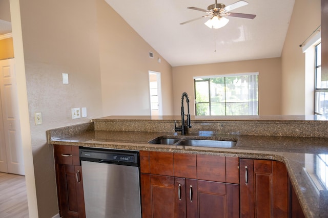 kitchen with ceiling fan, lofted ceiling, dark stone counters, a sink, and dishwasher