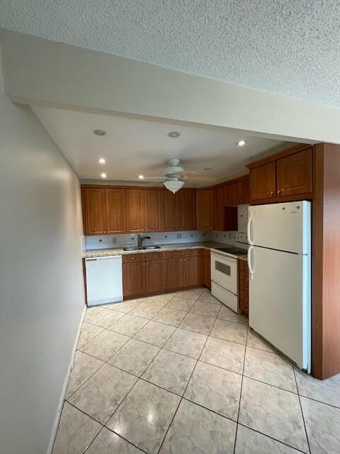 kitchen with a ceiling fan, white appliances, a sink, and light tile patterned floors