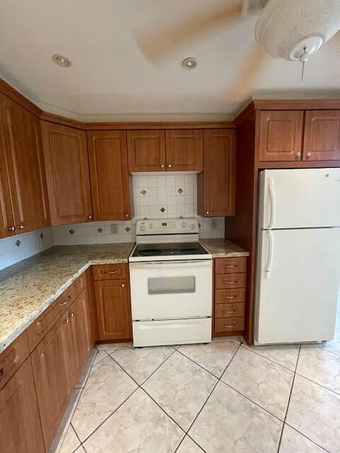 kitchen with white appliances, brown cabinetry, backsplash, and light tile patterned flooring