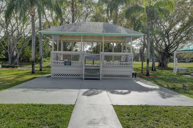 view of community featuring driveway, a yard, a wooden deck, and a gazebo