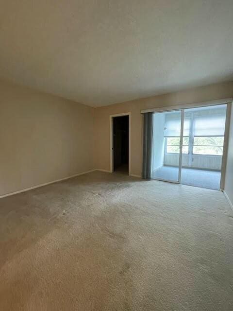 spare room with light carpet and baseboards