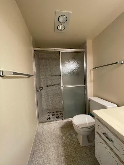 bathroom with a shower stall, toilet, and vanity