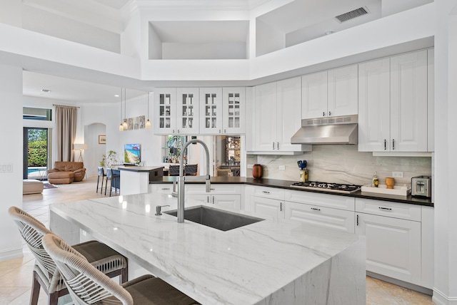 kitchen with under cabinet range hood, a breakfast bar, a sink, visible vents, and stainless steel gas stovetop