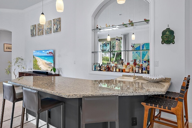 bar featuring arched walkways, bar, a sink, hanging light fixtures, and ornamental molding