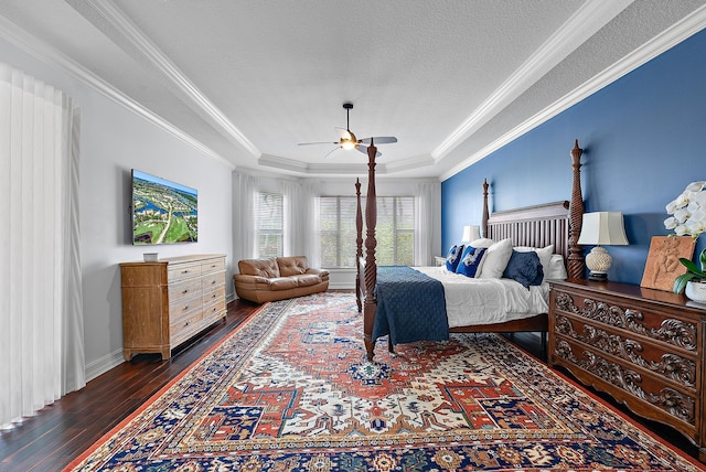 bedroom with a textured ceiling, a ceiling fan, ornamental molding, a tray ceiling, and dark wood finished floors