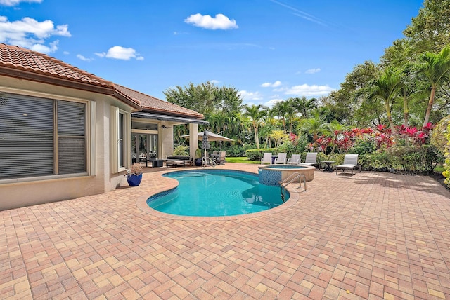 view of swimming pool featuring a pool with connected hot tub and a patio