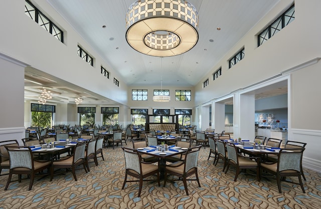 carpeted dining area featuring high vaulted ceiling and a notable chandelier