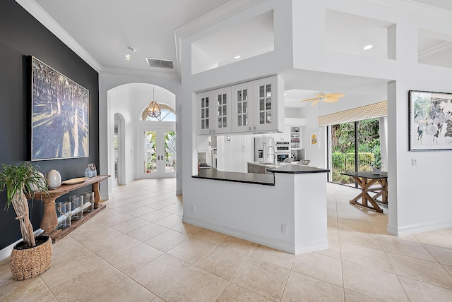 kitchen with visible vents, arched walkways, dark countertops, french doors, and light tile patterned flooring