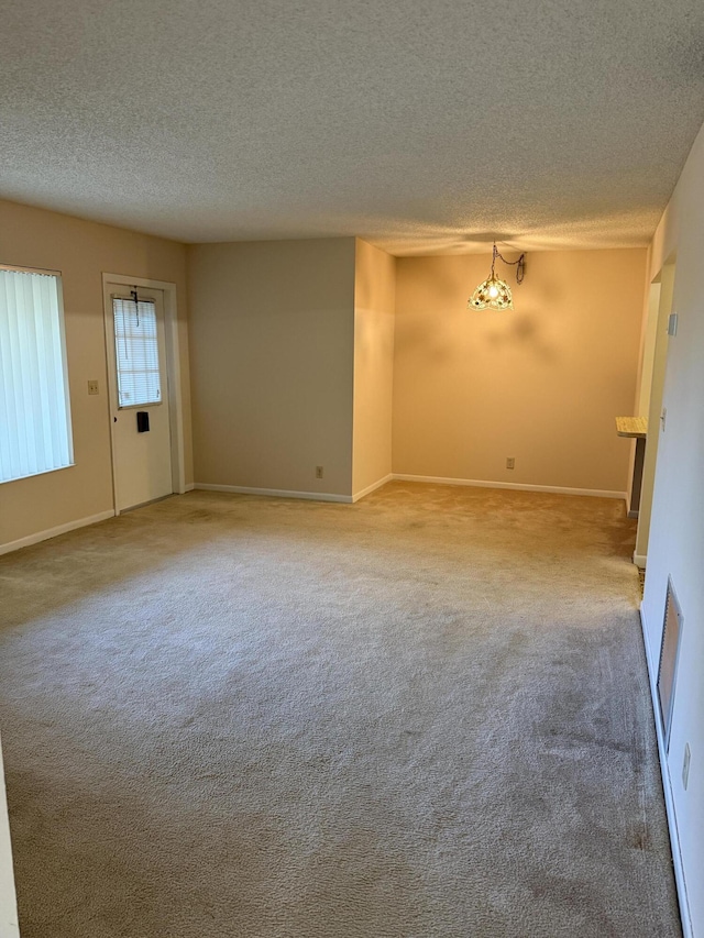 unfurnished room featuring a textured ceiling, carpet flooring, visible vents, and baseboards