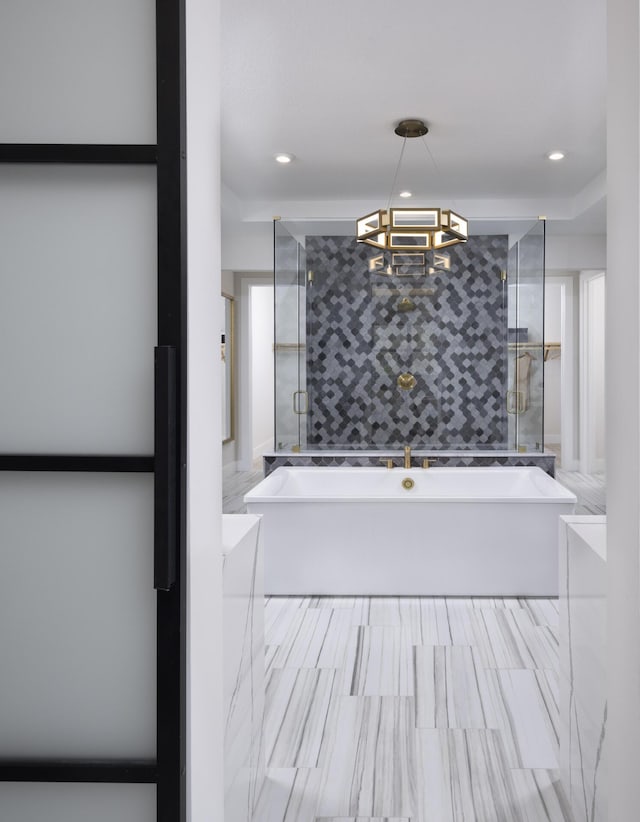 bathroom with a stall shower, a chandelier, a freestanding bath, and recessed lighting