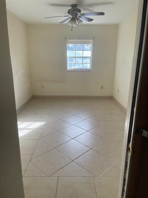 empty room featuring light tile patterned floors, ceiling fan, and baseboards