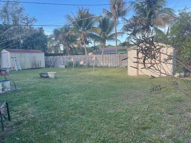 view of yard with a storage shed, an outbuilding, and fence private yard