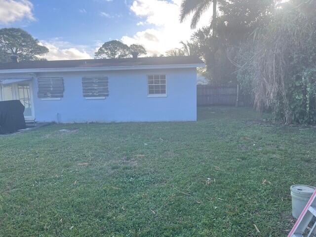 view of side of property with a lawn, fence, and stucco siding