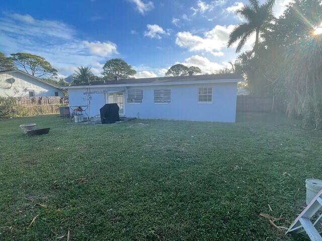 rear view of house featuring a lawn and fence