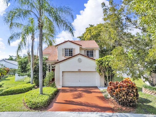 mediterranean / spanish home with a tile roof, stucco siding, an attached garage, a front yard, and driveway