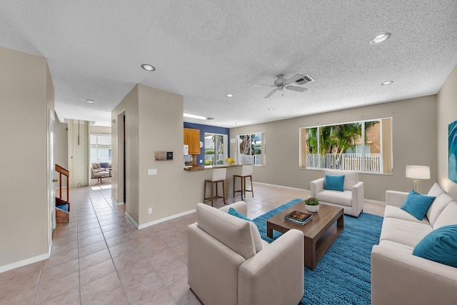 living area with light tile patterned floors, a textured ceiling, recessed lighting, visible vents, and baseboards