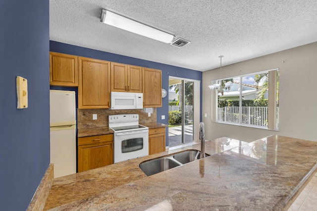 kitchen with pendant lighting, visible vents, decorative backsplash, a sink, and white appliances