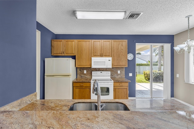 kitchen featuring a notable chandelier, white appliances, a sink, visible vents, and backsplash