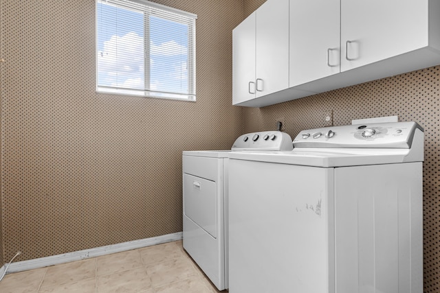 laundry area featuring cabinet space, light tile patterned floors, baseboards, and washer and dryer