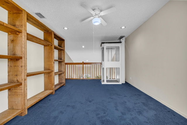 spare room with a textured ceiling, dark colored carpet, visible vents, and baseboards