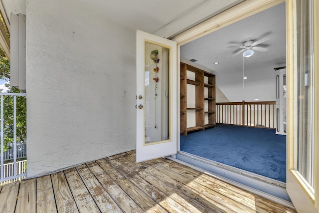 view of exterior entry with a ceiling fan and stucco siding