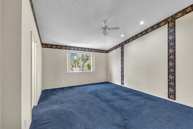 spare room featuring a textured ceiling, dark colored carpet, ceiling fan, and baseboards